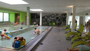 Ein Schwimmbeckenbereich mit mehreren Bahnen, Liegestühlen und einem Wandgemälde.