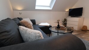 Ein modernes Wohnzimmer mit einer Couch, einem Couchtisch, einem Fernseher und einem Oberlicht.