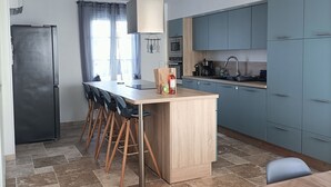 Eine moderne Küche mit einer zentralen Kochinsel, blauen Schränken und einem Essbereich mit Tisch und Stühlen.