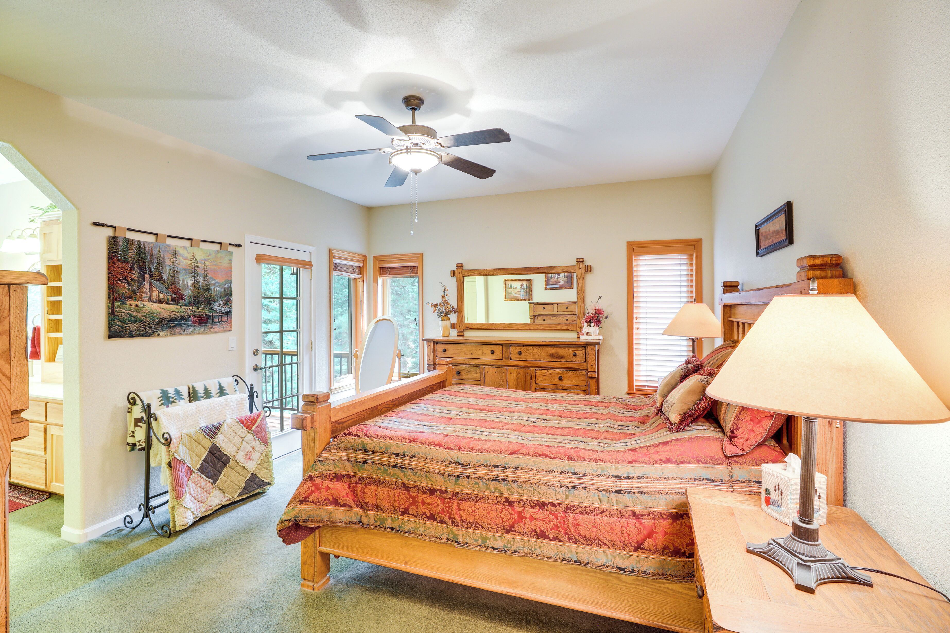 A bedroom with a bed, a ceiling fan, a dresser, a mirror, and a window with blinds.