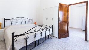 Een slaapkamer met een bed, een kledingkast en een open deur naar een badkamer.