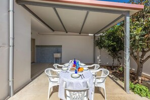 An outdoor dining area with a covered table set for four, surrounded by white chairs. - 4030 Villetta Giovy by Barbarhouse (Porto Cesareo)