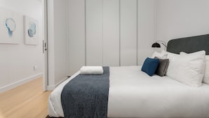 A modern bedroom with a bed, a bedside table with a lamp, and artwork on the wall. - The Rubik | Designer One-Bedroom in Cape Town (Cape Town)