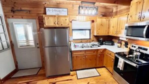 Una cocina compacta con armarios de madera, un refrigerador de acero inoxidable, un microondas y un horno.