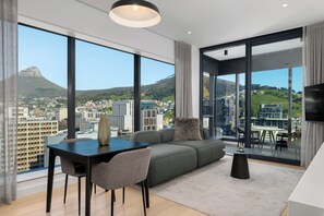 En moderne stue med et stort vindue der giver udsigt over byen, en sofa, et spisebord med stole og et lille sofabord.