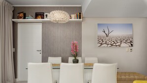 A dining area with a white table, chairs, and a vase of pink flowers. - Stunning Views From De Waterkant Apartment (Cape Town)