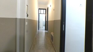 A narrow hallway with a light switch on the left wall, a vent on the right, and a door at the end. - Giuseppe Apartment (Rome)