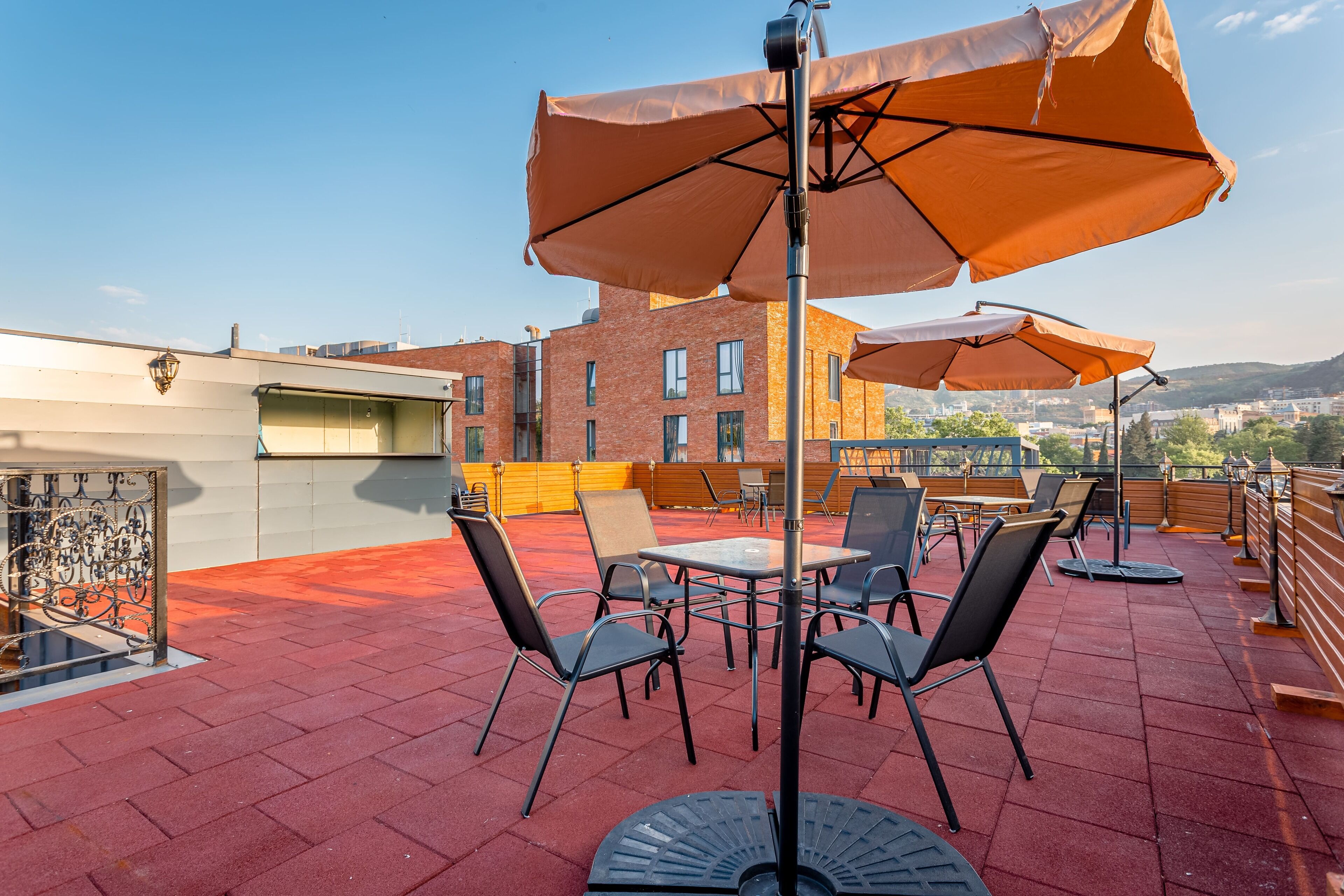 A rooftop terrace with outdoor seating, including tables and chairs, and large umbrellas.
