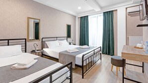 A hotel room with two beds, a desk, and a chair. There is a mirror, a lamp, and an air conditioning unit on the wall. - Monument1880 (Tbilisi)
