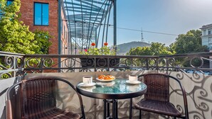 A balcony with wicker chairs, a round table, and two cups of coffee. - Monument1880 (Tbilisi)