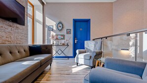 A modern living room with a sofa, armchair, and a blue door. - Monument1880 (Tbilisi)
