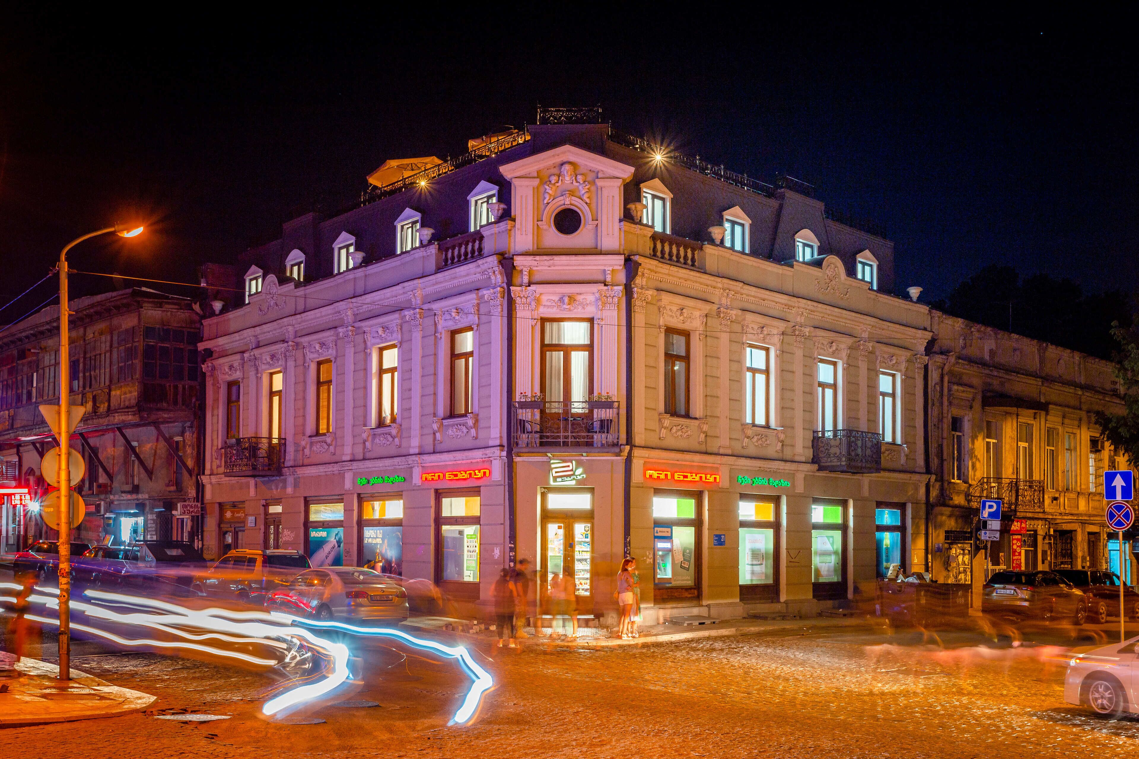 A historic building with multiple storefronts, a prominent entrance, and a balcony.