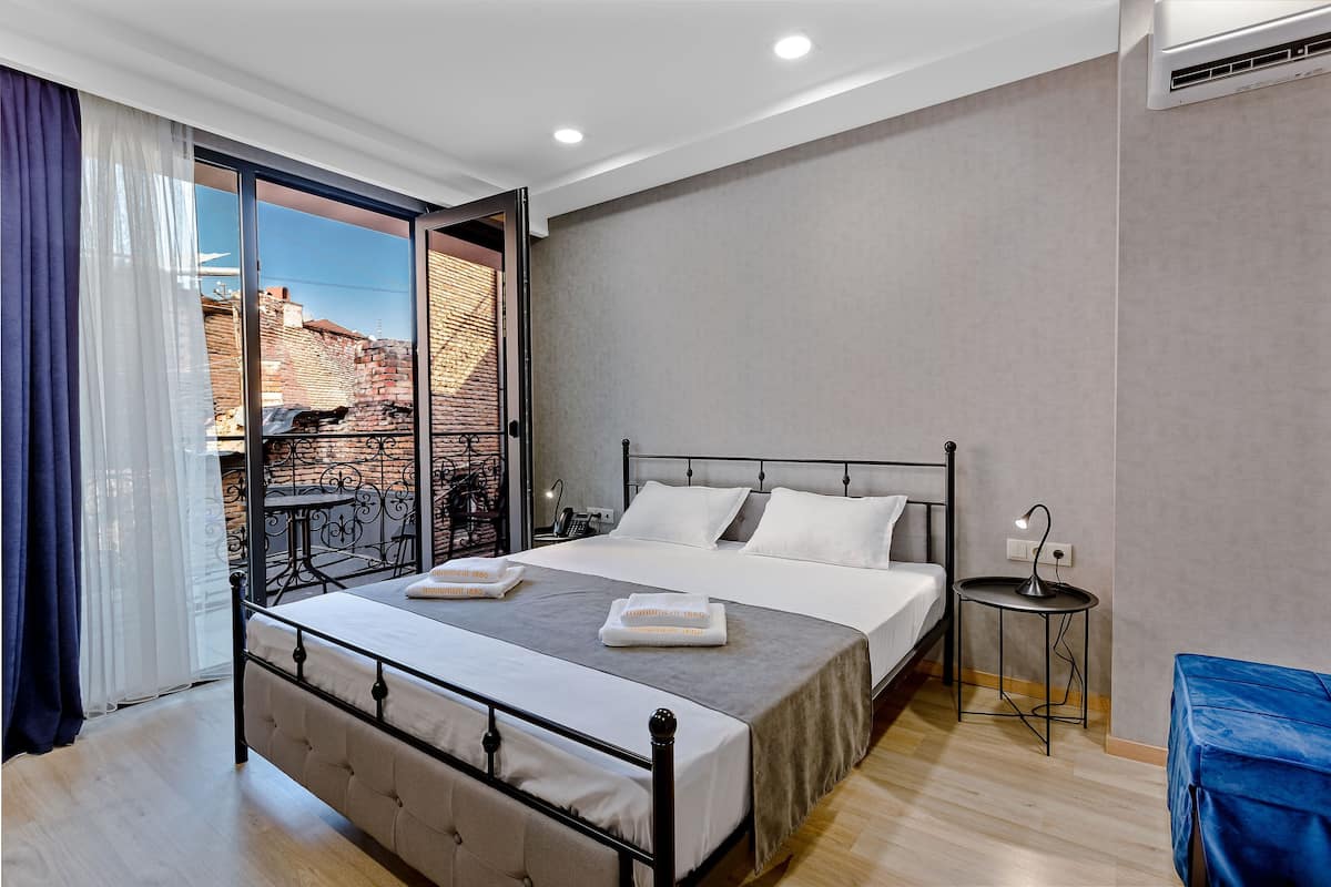 Ein Schlafzimmer mit Bett, Nachttisch und Blick ins Freie.