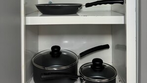 Un meuble de cuisine contenant deux casseroles et une poêle.