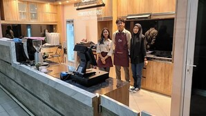 A modern kitchen area with a cash register, a coworking space sign, and a counter with a coffee machine. - Karana Guesthouse Syariah Bandung & Luang Cafe (Bandung)