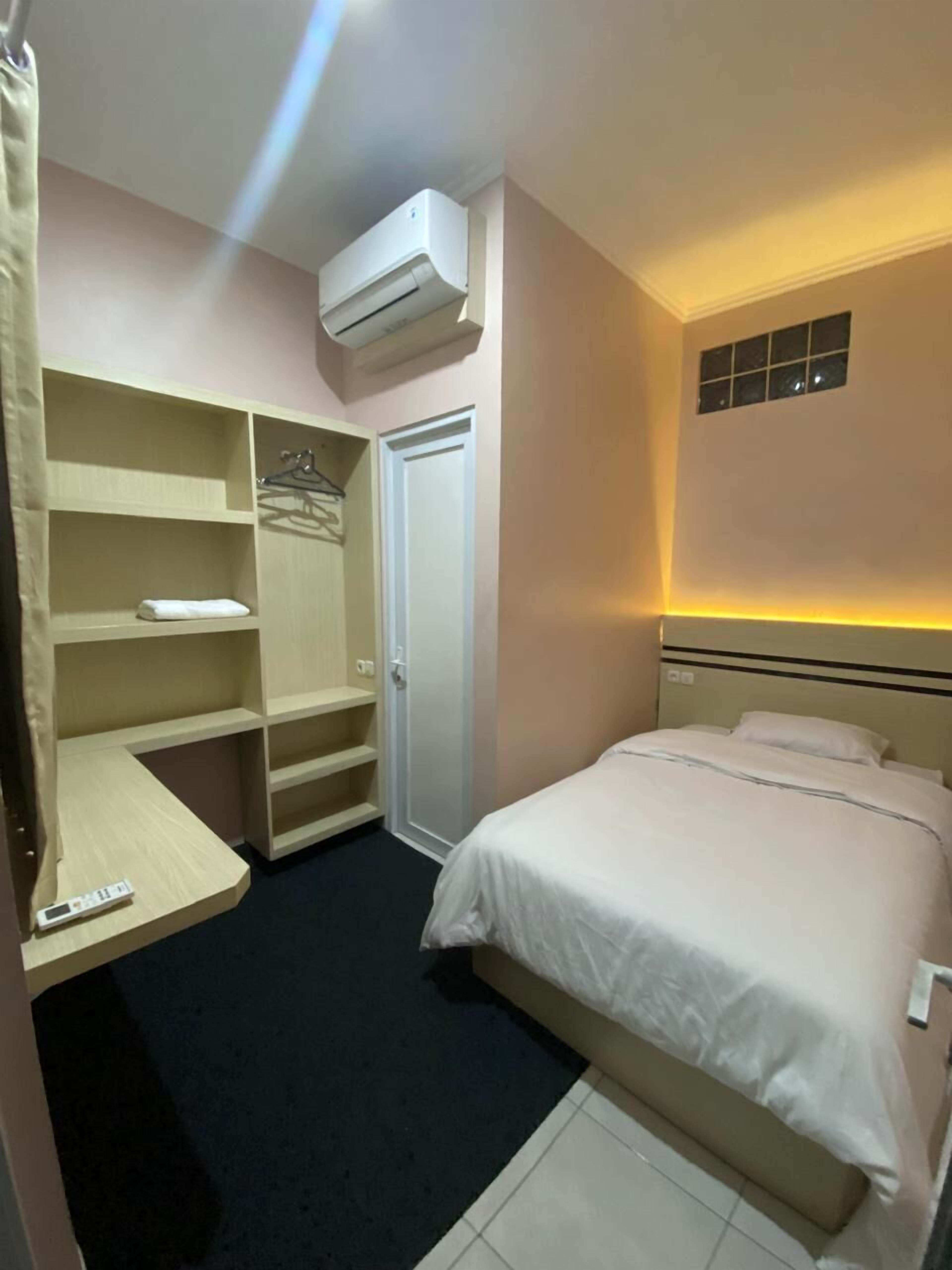 A bedroom with a bed, a wardrobe, and an air conditioning unit.