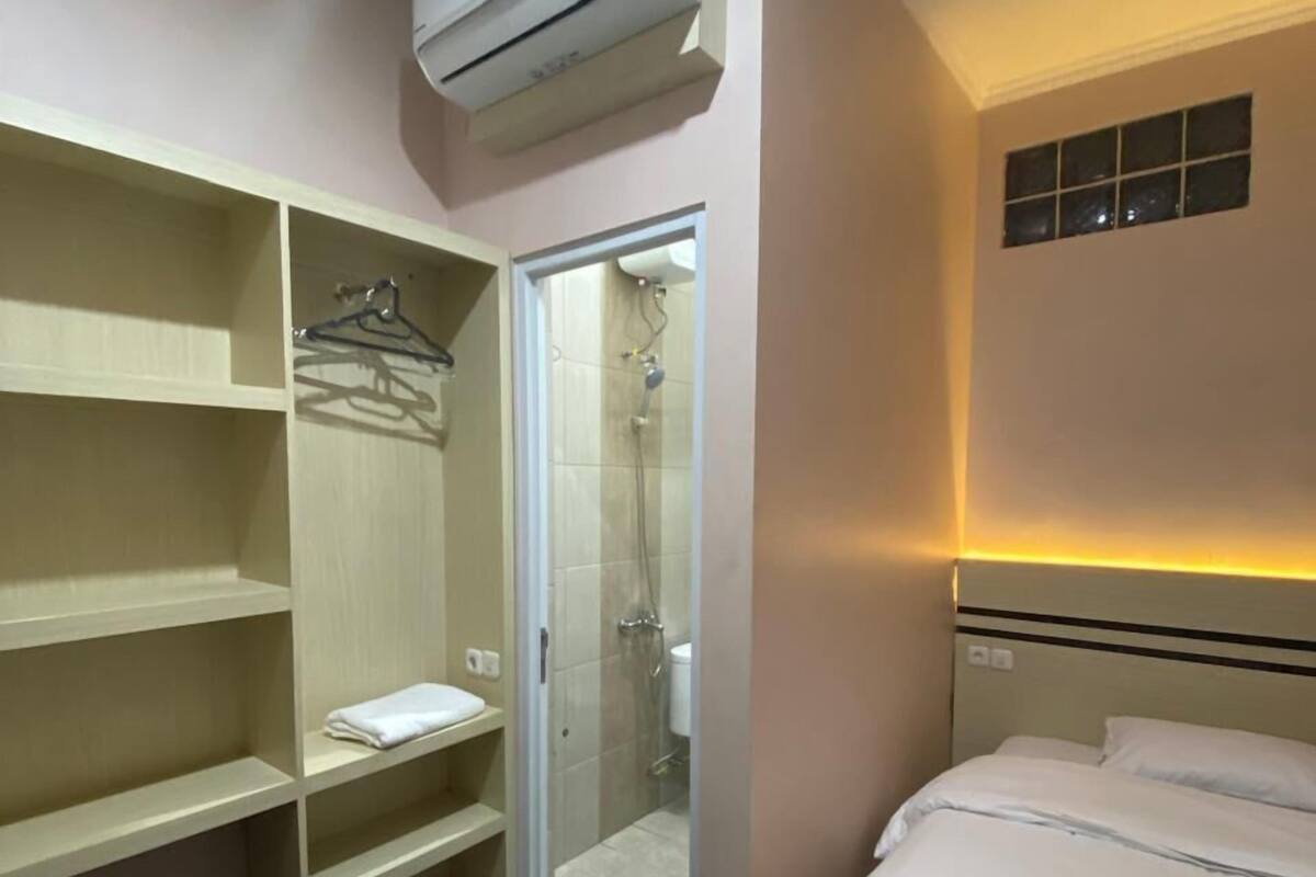 A hotel room with a bed, a walk-in closet, and a shower area.