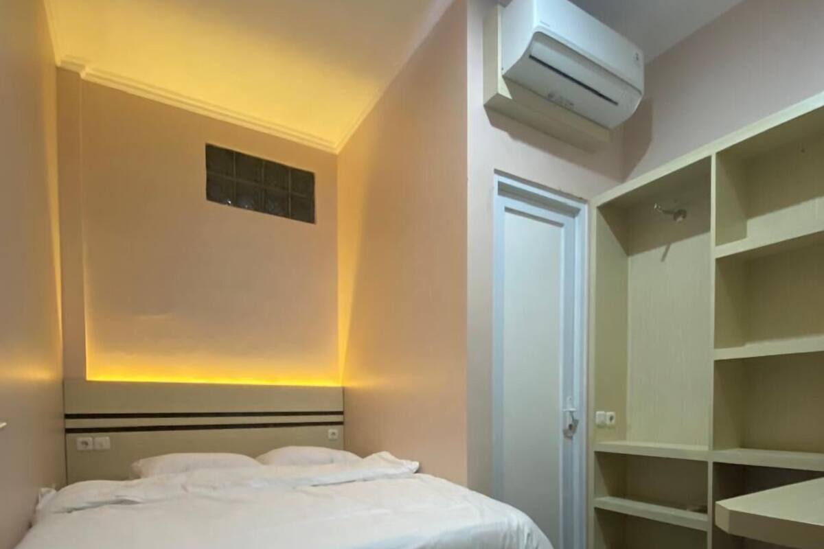 A hotel room with a bed, a wardrobe, and an air conditioning unit.