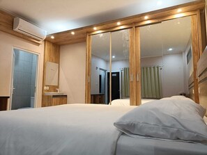 Un dormitorio con cama, espejo, armario y aire acondicionado.