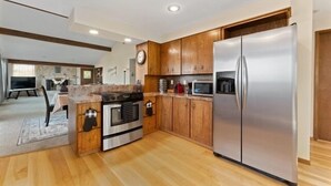 Een moderne keuken met houten kastjes, roestvrijstalen apparatuur en een inbouwmagnetron.