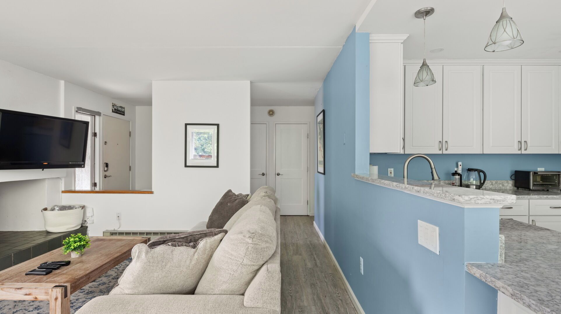 A modern living room with a sofa, a coffee table, and a TV mounted on the wall.