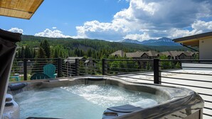 Un jacuzzi con vistas a montañas y una terraza de madera.