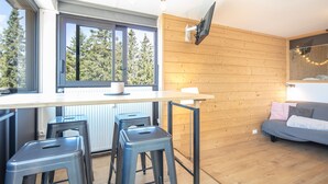 Eine moderne Küche mit einem großen Fenster, Holzvertäfelung und einem grauen Sofa.
