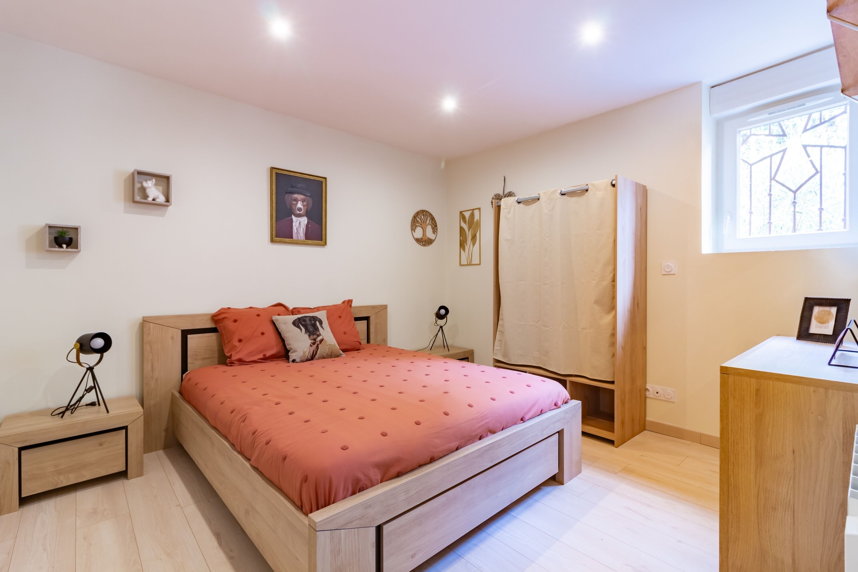 A bedroom with a wooden bed, a nightstand, a desk, a window with a view, and a shower area.