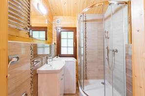 Enjoy a refreshing shower in the bathroom, featuring a glass-enclosed shower area with a handheld showerhead and a washing machine.