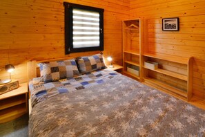 Relax in a serene bedroom with a large bed, wooden wardrobe, and framed artwork.