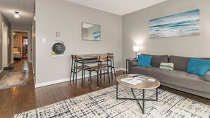 A modern living room with a grey sofa, a coffee table, and a dining area with a table and chairs.