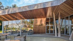 An outdoor seating area with tables and chairs, a wooden facade, and a sign reading "Vocalab". - Elegant Nature Retreat (Antoing)
