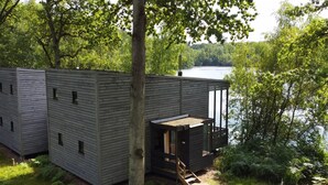 A cabin with a deck overlooking a lake, surrounded by trees. - Elegant Nature Retreat (Antoing)