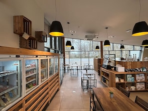 Enjoy a warm atmosphere in our café with a long counter, multiple seating areas, and large windows offering a view of the outdoors.