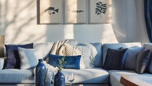 Un salon moderne avec un canapé bleu clair, des coussins décoratifs et des œuvres d’art encadrées accrochées au mur.