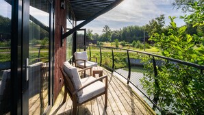 A wooden deck with two white cushioned chairs and a glass door leading to a view of a green landscape. - Escape With Pool & Charm (Antoing)