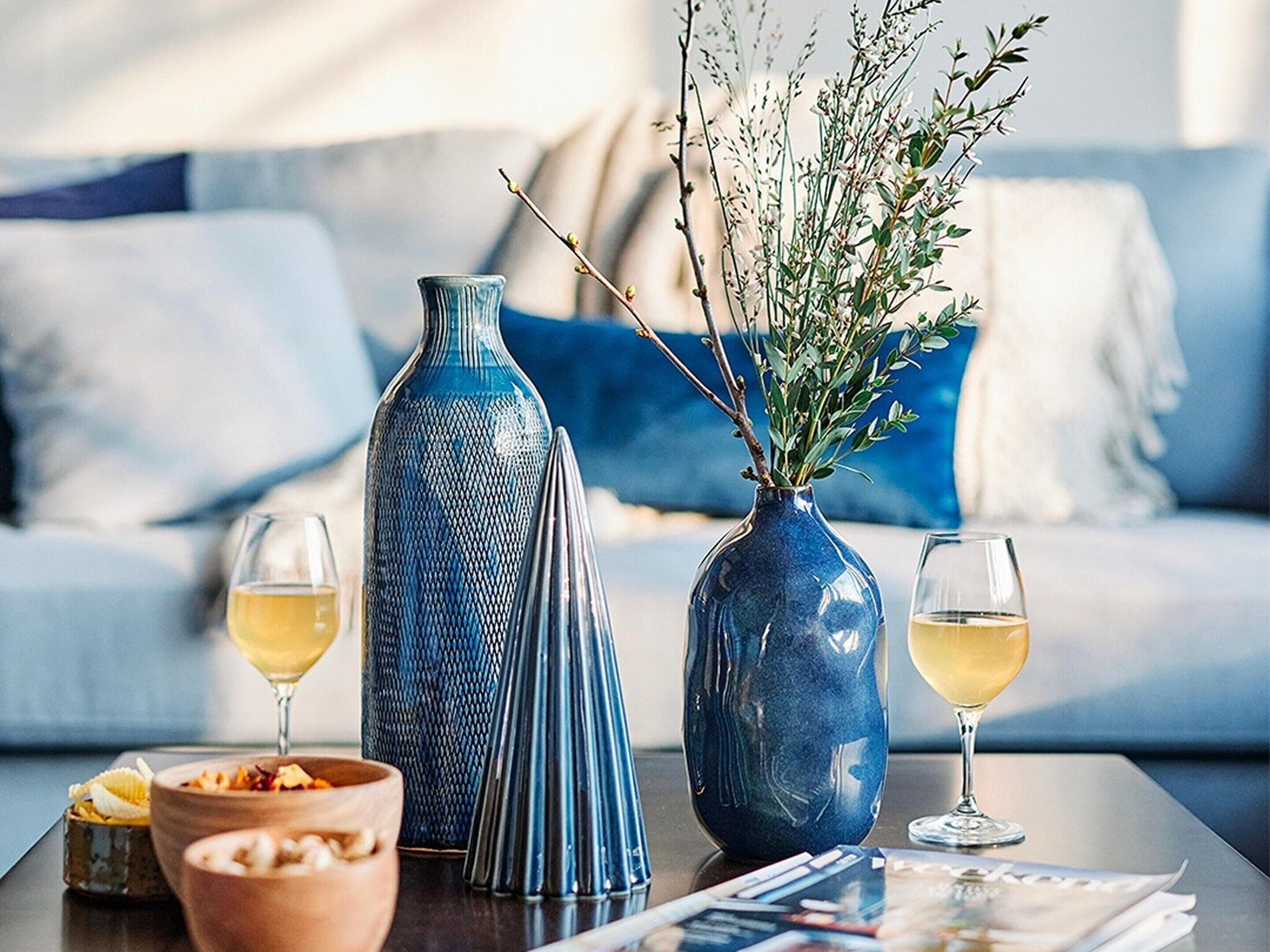 A modern living room with a sofa, two vases, and two glasses of white wine on a coffee table.