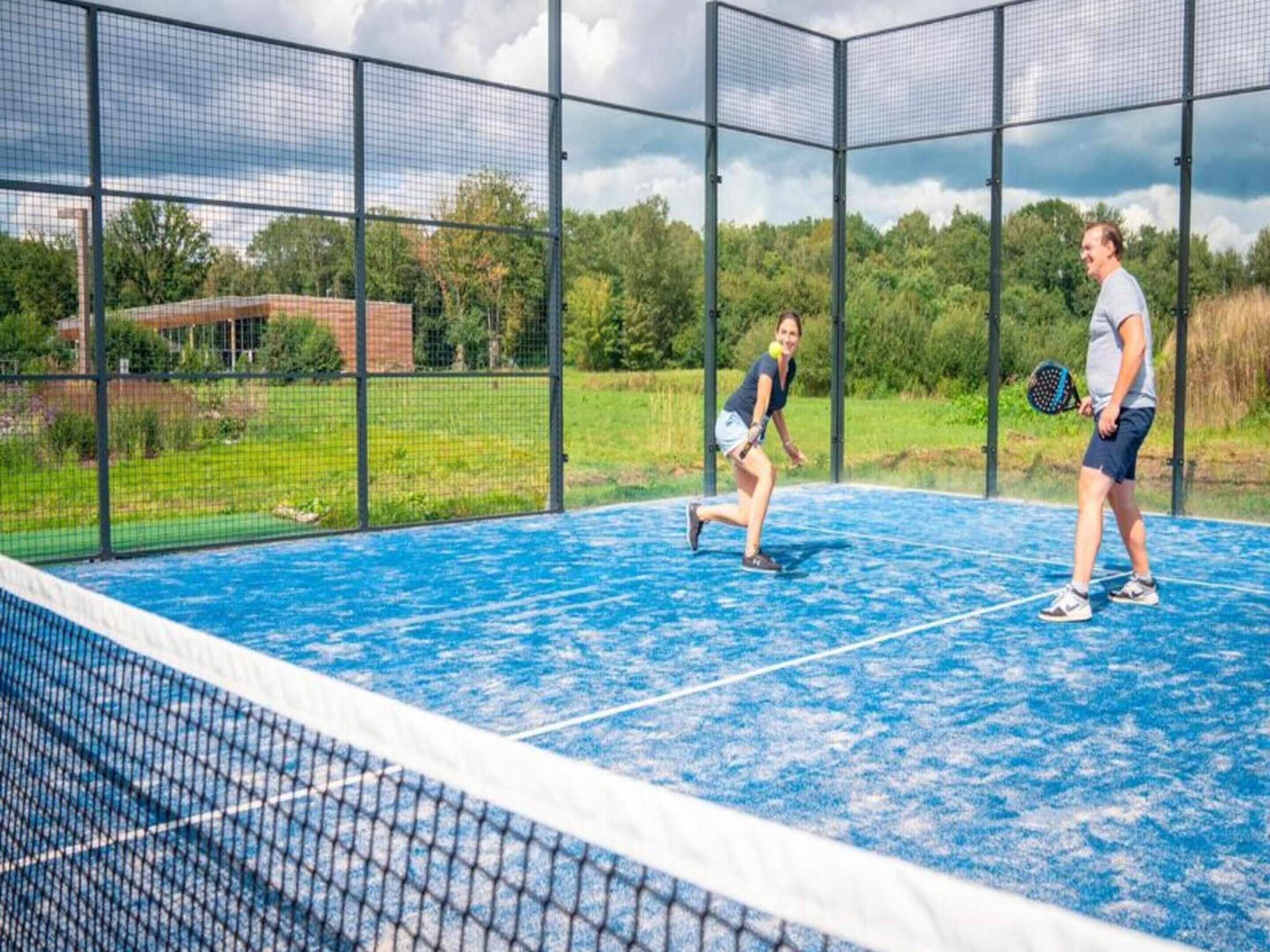 Una cancha de tenis al aire libre con red y vallas.