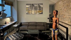 Un salon moderne avec un canapé en cuir, une table basse en verre et une sculpture en bois.
