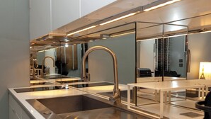 Une cuisine moderne dotée d’un évier en acier inoxydable, d’un robinet double et d’un plan de travail blanc.