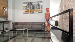 Un salon moderne avec une table basse en verre, un canapé en cuir et un mur en briques.