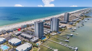 Vista aérea de una zona hotelera costera con edificios altos, una playa y un puerto deportivo.