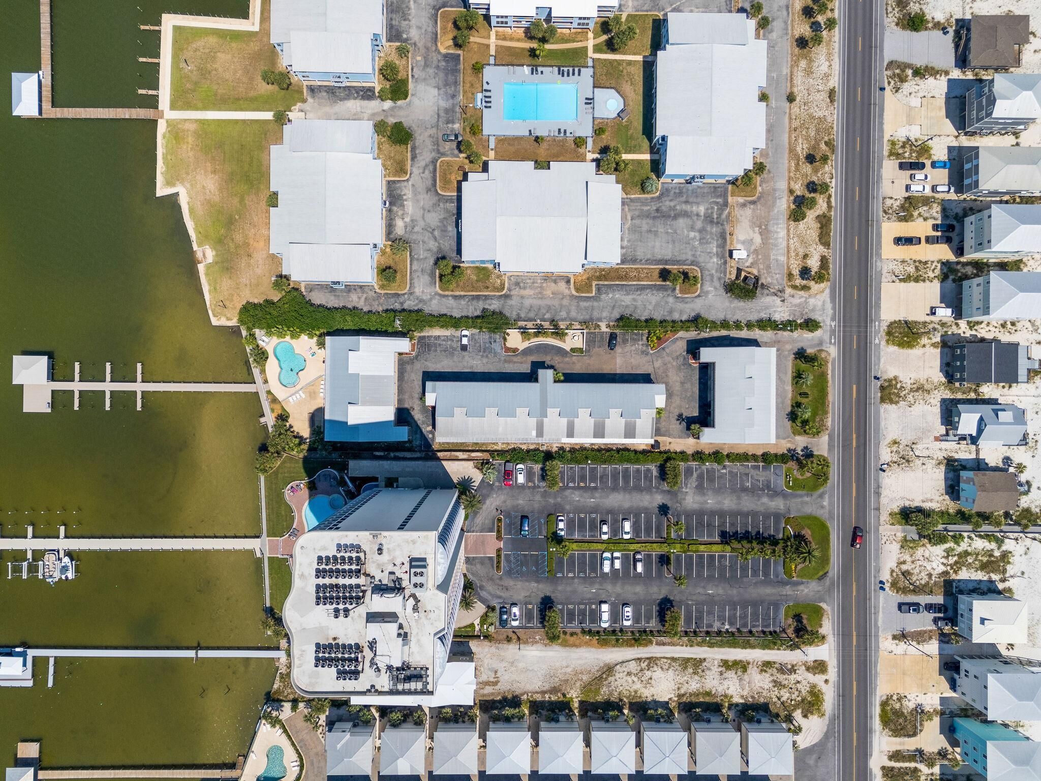 Ein Luftbild eines Geschäftsgebäudes mit Parkplatz, Schwimmbad und einer Anlegestelle, die sich über das Wasser erstreckt.