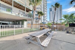 Un edificio de varios pisos con balcones, una mesa de picnic y palmeras.