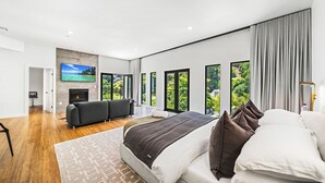 Une chambre moderne avec un grand lit, un canapé, une télévision et une cheminée.
