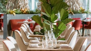 Un restaurant avec une longue table dressée pour le repas, entourée de chaises rouges.