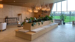 Un intérieur moderne avec un plafond en bois, de grandes fenêtres, un jardinier central agrémenté de plantes et un espace salon.