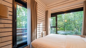 A bedroom with a large bed, wooden walls, a window with curtains, and a view of trees. - Woodland Retreat, Antoing (Antoing)