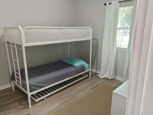 A bunk bed in a room with a window and a view of greenery outside.