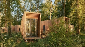 A wooden cabin with a glass door, surrounded by dense forest. - Belvilla Picturesque Cabin in Nature (Antoing)